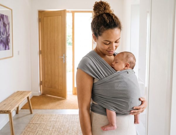 Mãe usa o sling para bebê com o rosto do bebê sempre visível