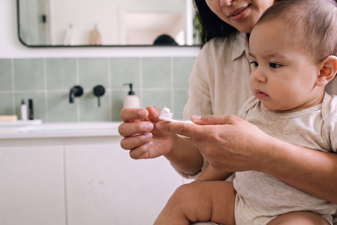 Mãe mede a quantidade certa de pasta na escova do bebê