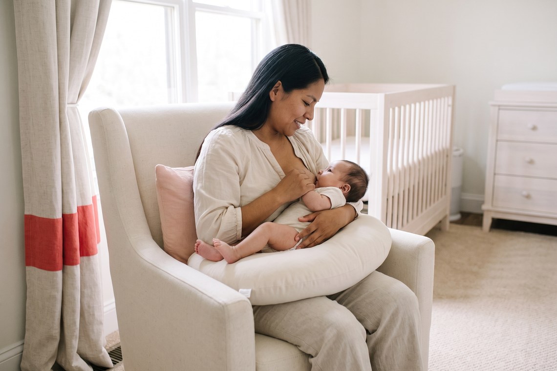 Mãe amamentando o bebê apoiada na almofada de amamentação Yogi Moon