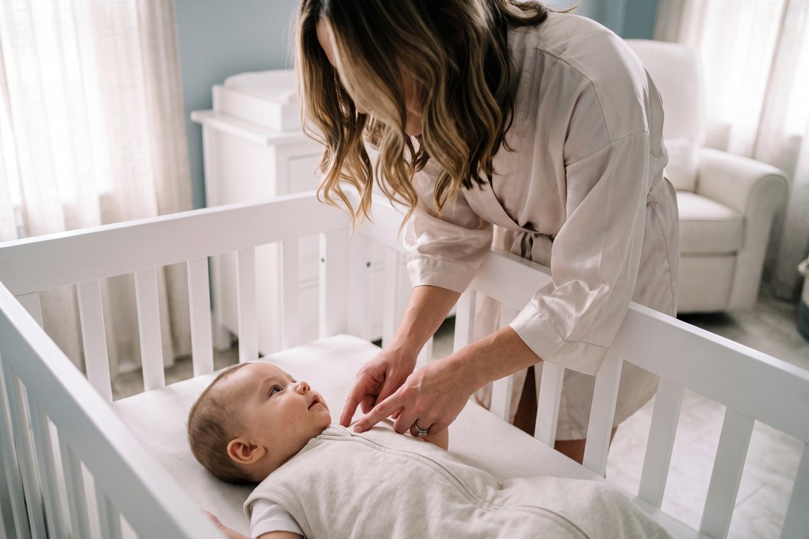 Mãe confere o ajuste do saco de dormir do bebê nos ombros